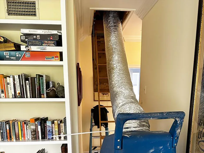 Air duct cleaning hose connected to a HEPA machine inside a home