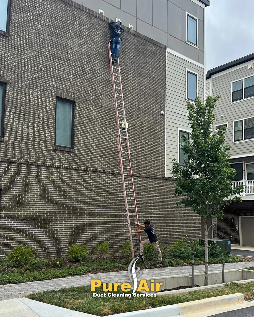 Technician on a tall ladder cleaning a dryer vent on a multi-story building