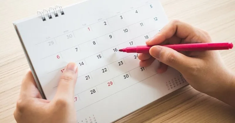Hand marking a date on a calendar